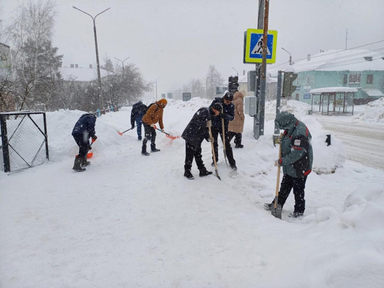 Сотрудники администрации города расчищают от снега пешеходный переход и тротуар около школы №6.