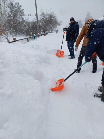 Сотрудники администрации города расчищают от снега пешеходный переход и тротуар около школы №6.